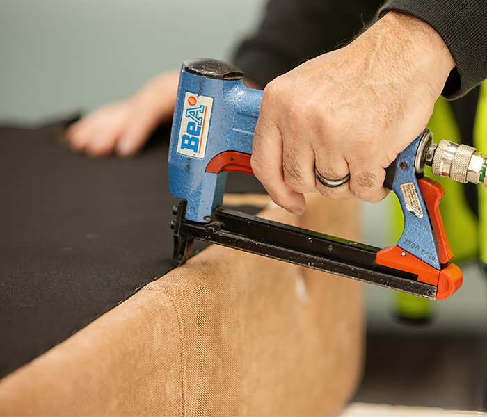 Close up of staple gun securing upholstery